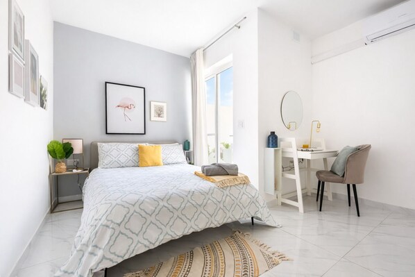Un dormitorio moderno con cama, mesita de noche y escritorio con silla.