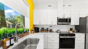 A modern kitchen with white cabinets, stainless steel appliances, and a large window overlooking greenery. - *NEW* Pool table, fenced backyard, 1 mi to downtown, 5 mi to beach, 3BD/2BA (St. Augustine)