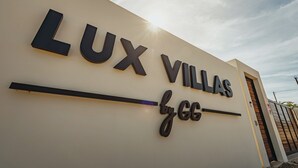 Schild für 'LUX VILLAS by GG' mit modernem Design und einem klaren Himmel im Hintergrund.