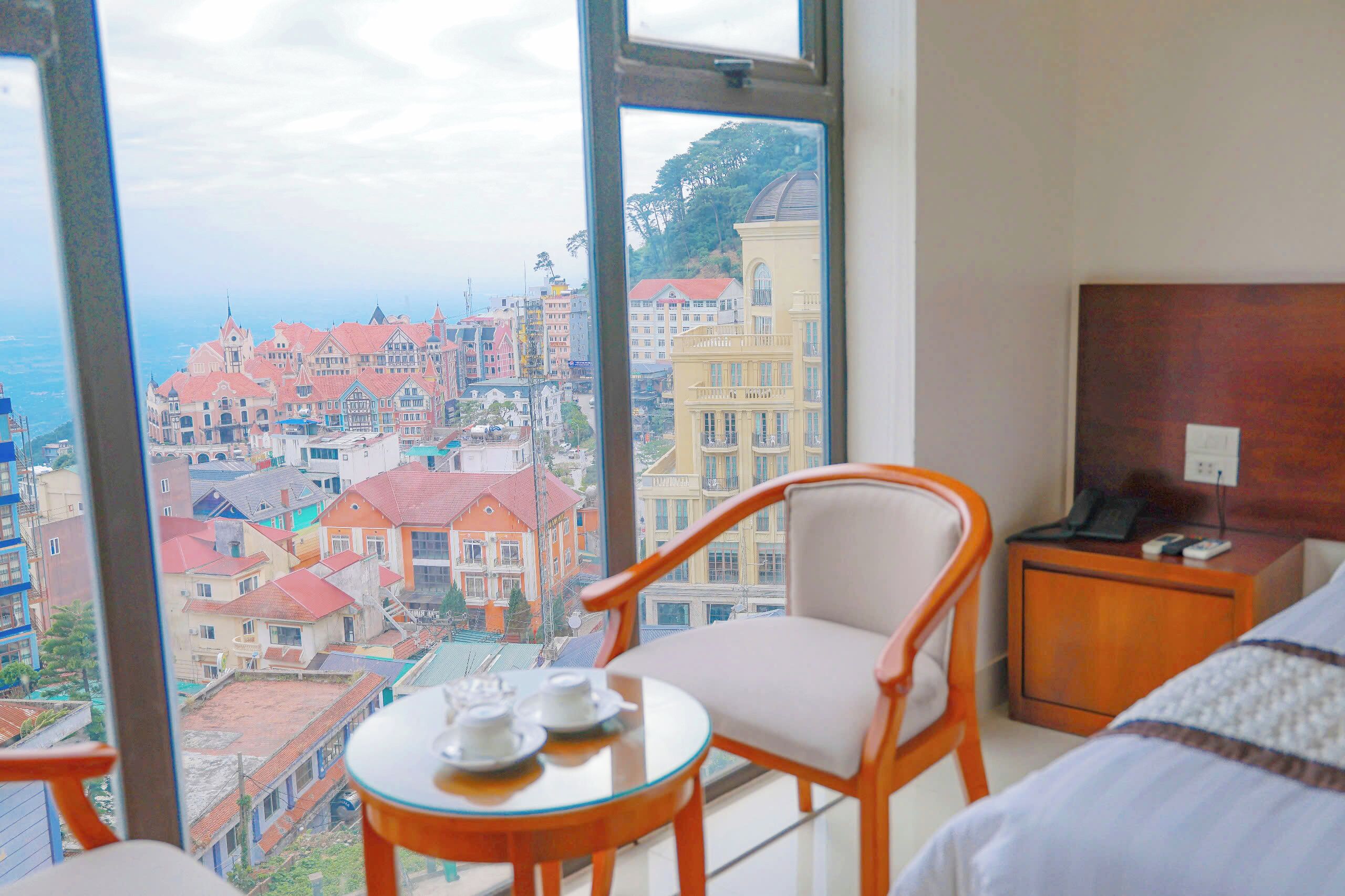 Une chambre d’hôtel dotée d’une grande fenêtre donnant sur la ville.