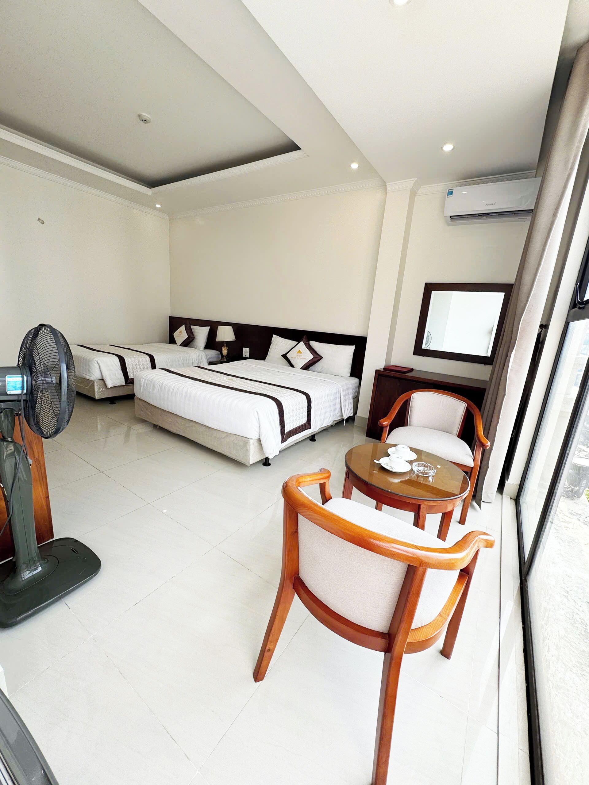 Een hotelkamer met een bed, nachtkastje, stoel en een ventilator.
