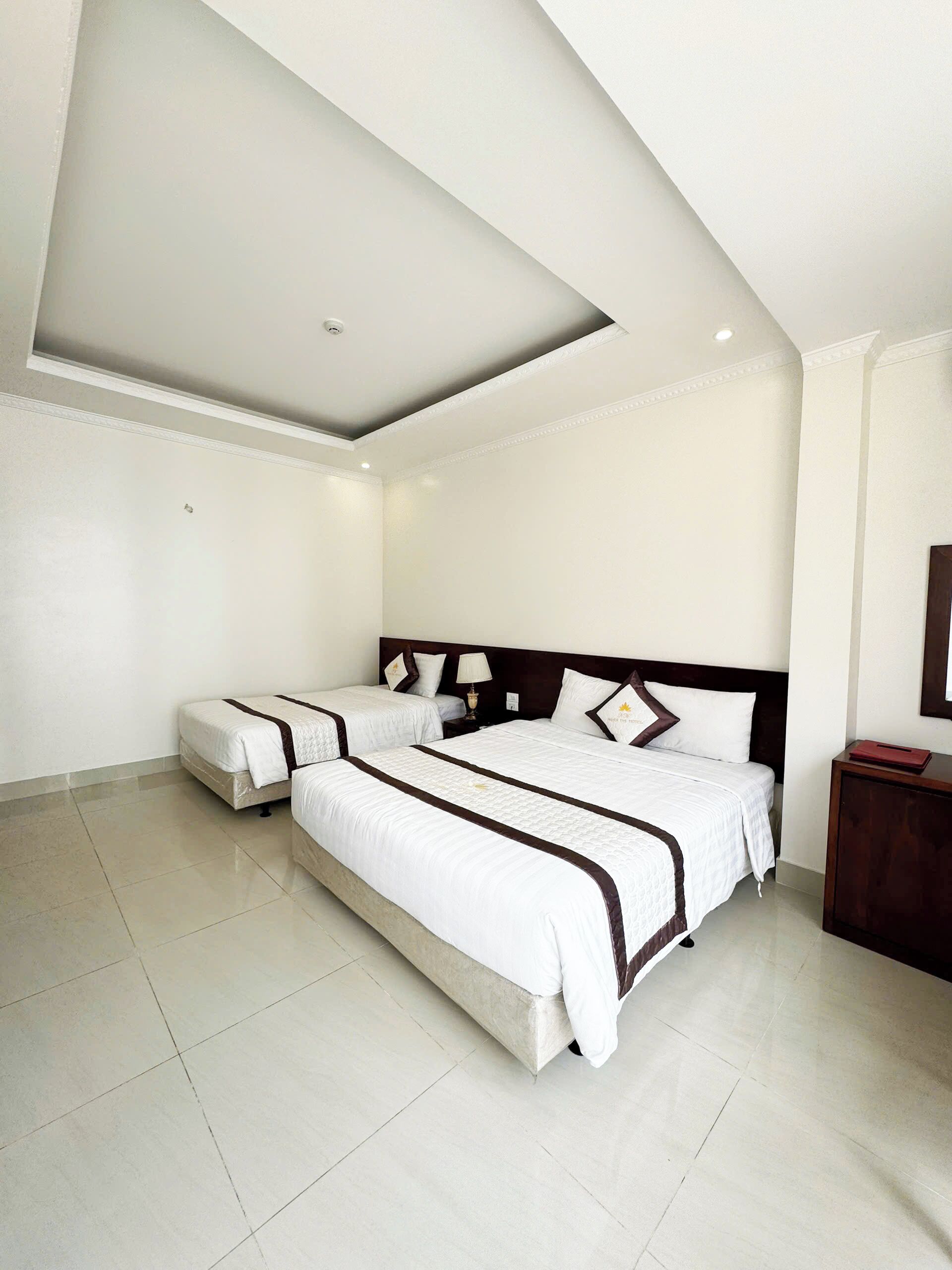 A hotel room with a large bed, a smaller bed, a nightstand, a mirror, and a ceiling light.