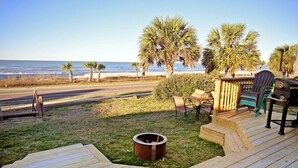 A wooden deck with a fire pit, outdoor seating, and palm trees overlooking the ocean. - Stay in a Historic Beachfront Gem with Unmatched Ocean Views (Port St. Joe)