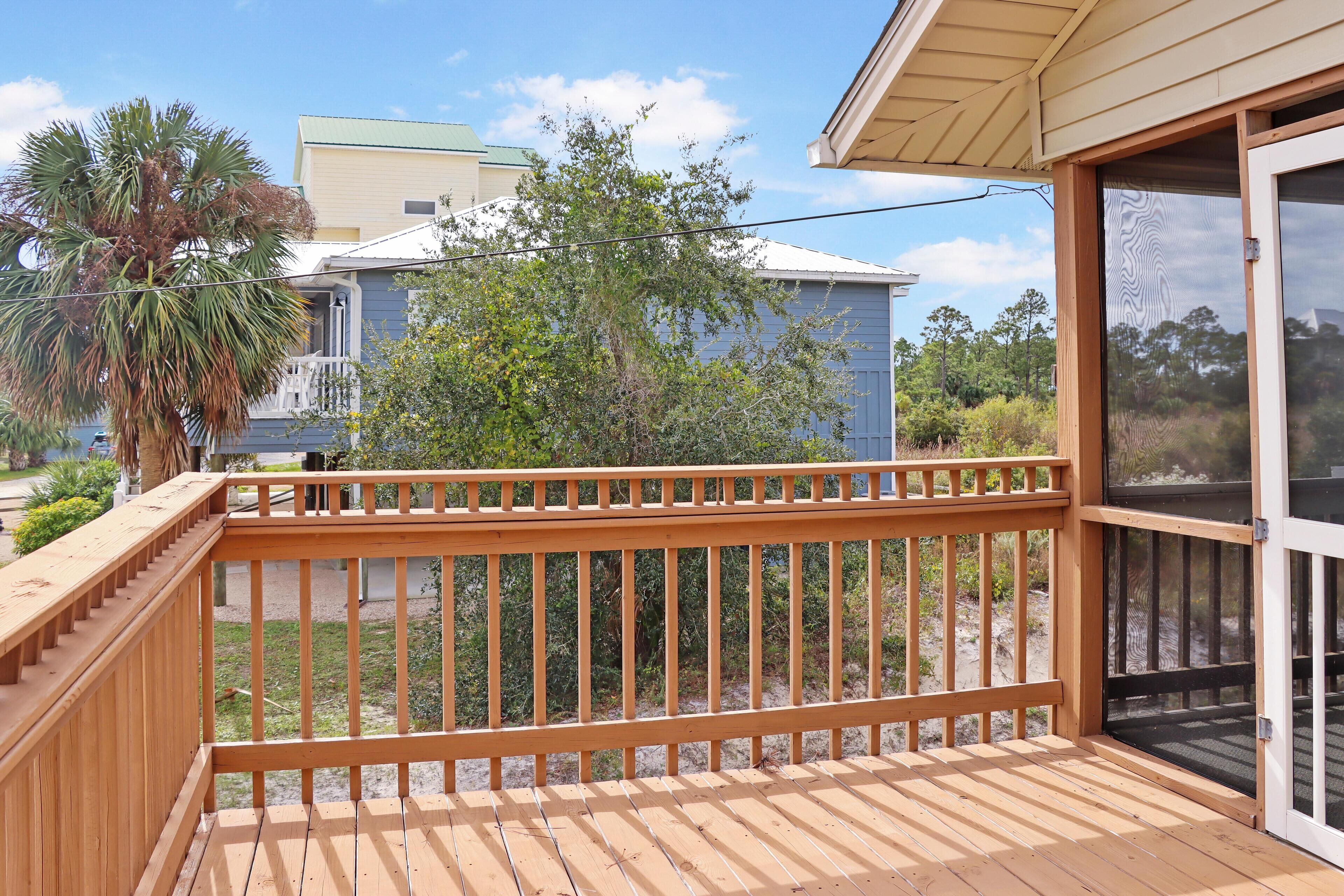 A wooden deck with a glass door leading to a covered area.