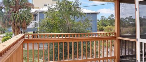 A wooden deck with a glass door leading to a covered area.