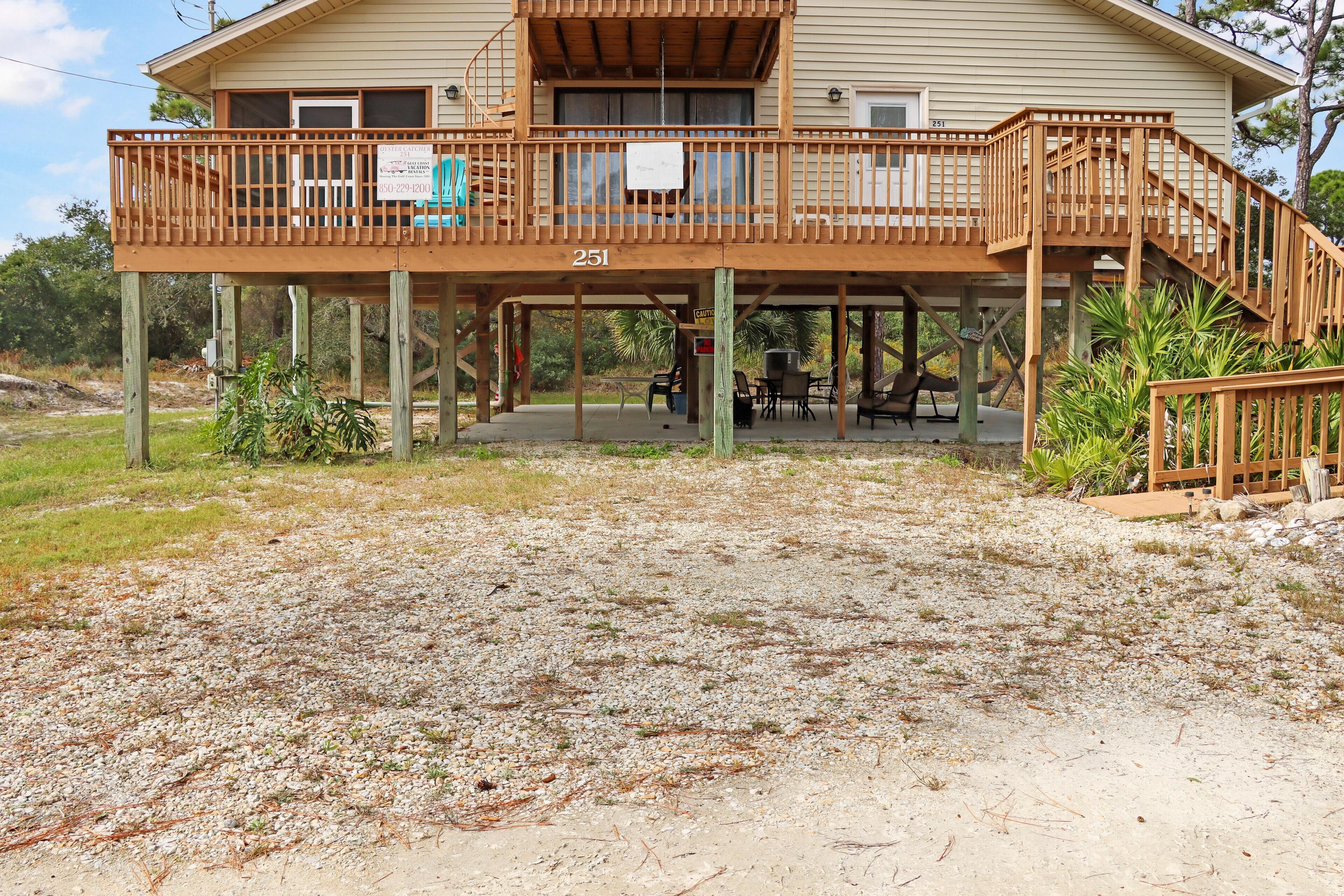 A two-story house with a wooden deck, number 251, featuring outdoor seating and a small table.