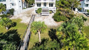 Une propriété de deux étages située en bord de mer, dotée d’une terrasse couverte et de plusieurs balcons.