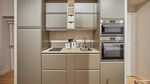 A compact kitchen with built-in appliances, including a toaster, kettle, and double oven.
