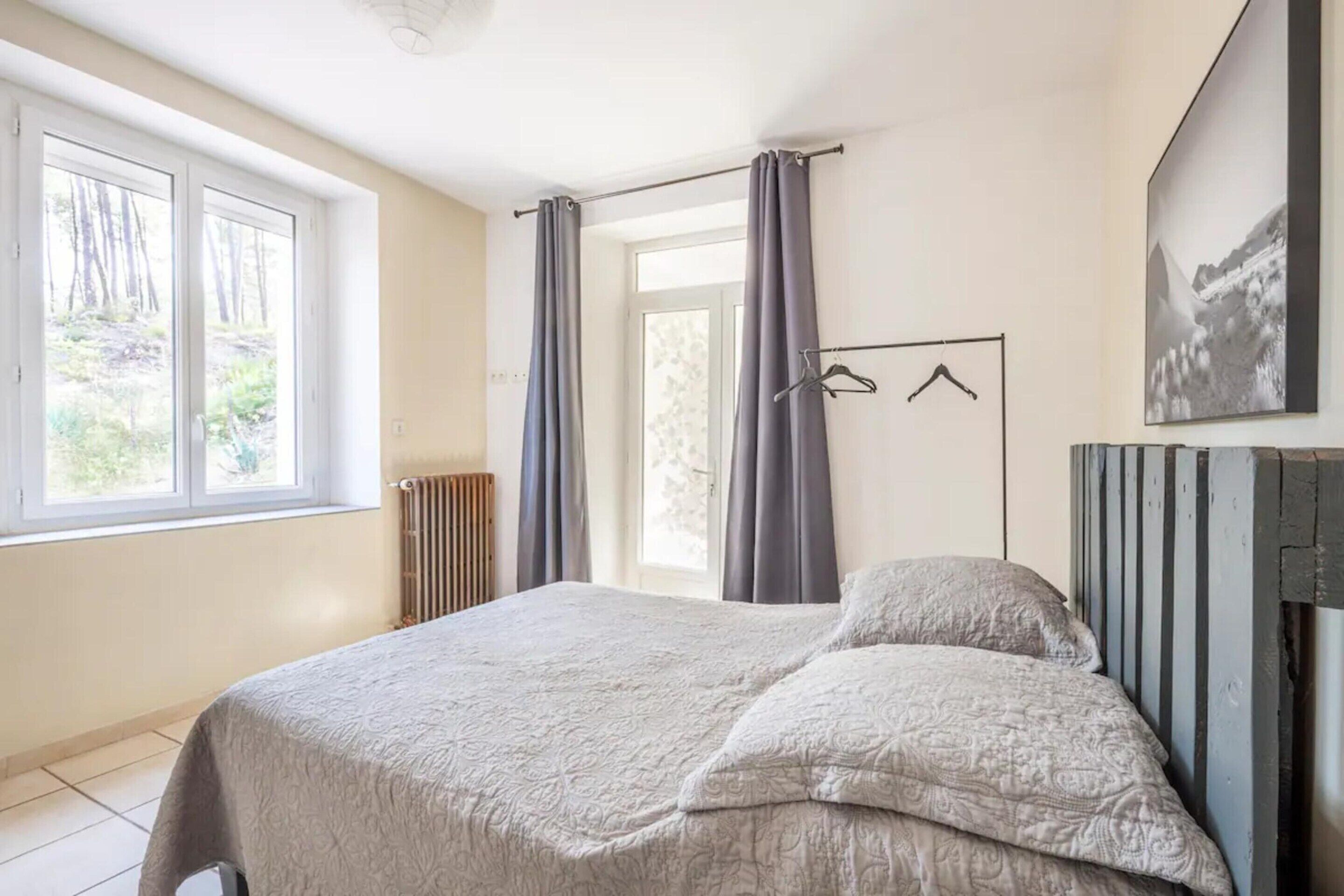 A bedroom with a bed, a radiator, a window, and a door.