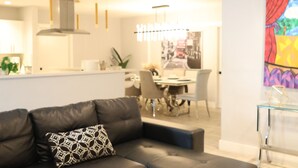 Un soggiorno moderno con un divano in pelle scura, un tavolino da caffè in vetro e un quadro astratto dai colori vivaci appeso al muro.