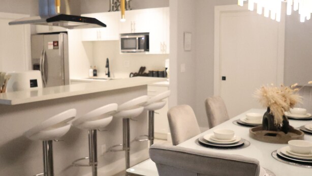 Una cucina moderna con isola centrale, sgabelli da bar e un tavolo da pranzo per quattro persone.