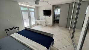 A bedroom with a bed, a desk, a chair, a TV, and a sliding door. - Kasa Metropolios 4-bedroom house w AC, WiFi, 2 car garage 7 minutes from airport (Carolina)
