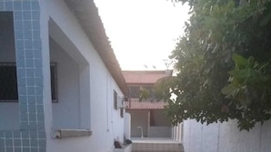 A courtyard with stone paving, a tiled wall, and a building with a tiled roof. - Harmô Hostel Cultural (Conde)