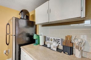 A kitchen with a black refrigerator, a green coffee maker, and a 'HOME' sign on the wall.
