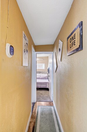 A hallway with a door leading to a bedroom, a thermostat, and motivational wall art. - Private 2 Bedroom Guesthouse Near Fremont! (Las Vegas)