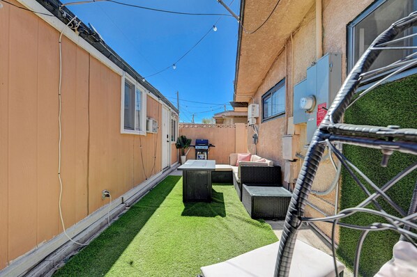 A narrow outdoor patio with artificial grass, a grill, and outdoor furniture. - Private 2 Bedroom Guesthouse Near Fremont! (Las Vegas)