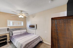 A bedroom with a bed, a ceiling fan, a mounted TV, and a window with blinds. - Private 2 Bedroom Guesthouse Near Fremont! (Las Vegas)