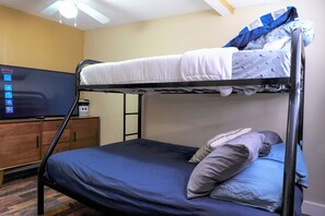 Ein Etagenbett mit Fernseher auf einer Holzkommode, ein Deckenventilator und eine Wand mit Netflix-Logo.