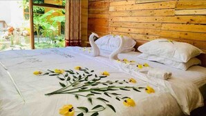 A bed with a swan and flowers, wooden walls, and a view of greenery. - Dhontakuru Guesthouse (Dhidhdhoo)