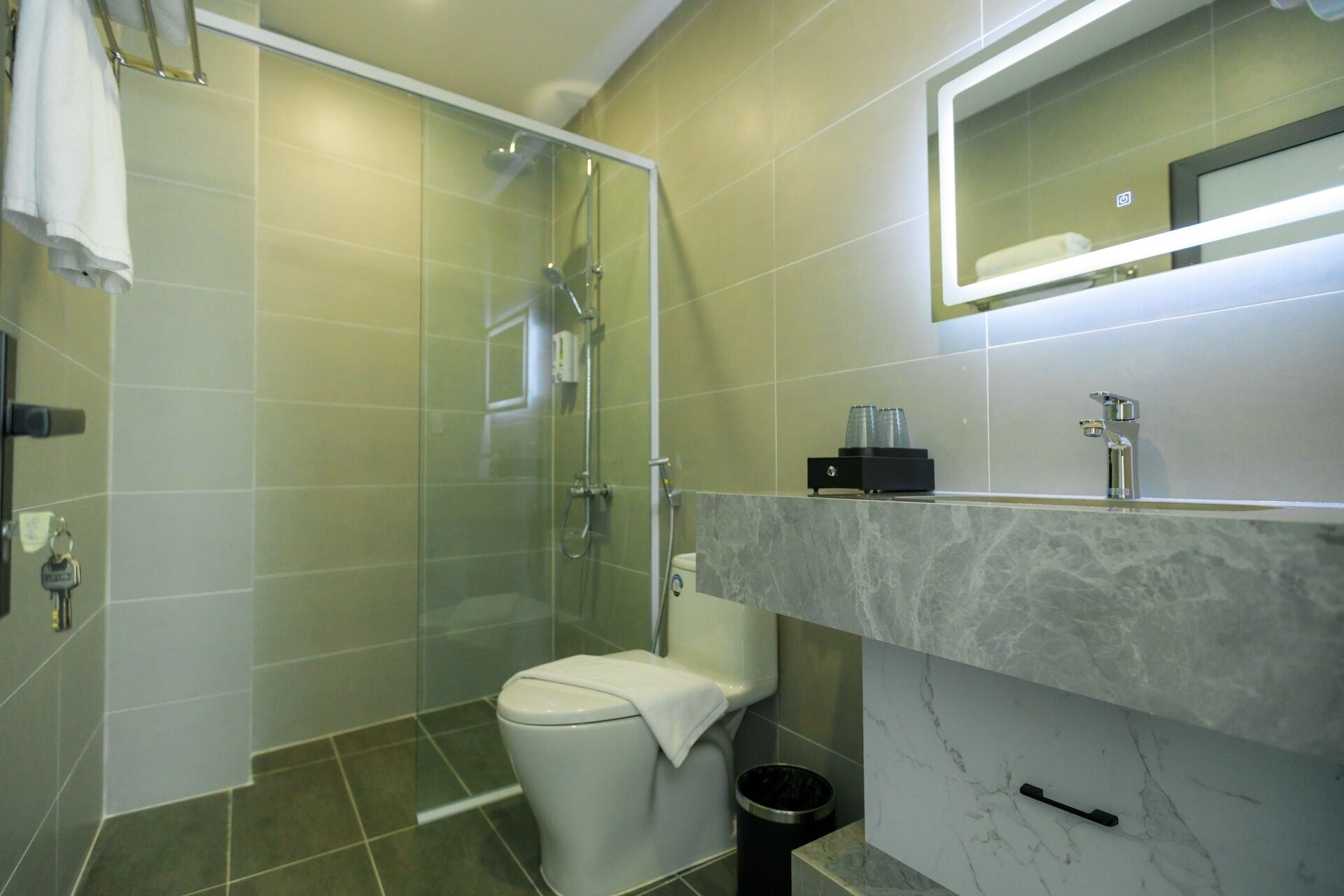 A modern bathroom with a glass shower enclosure, a toilet, and a marble vanity with a mirror.