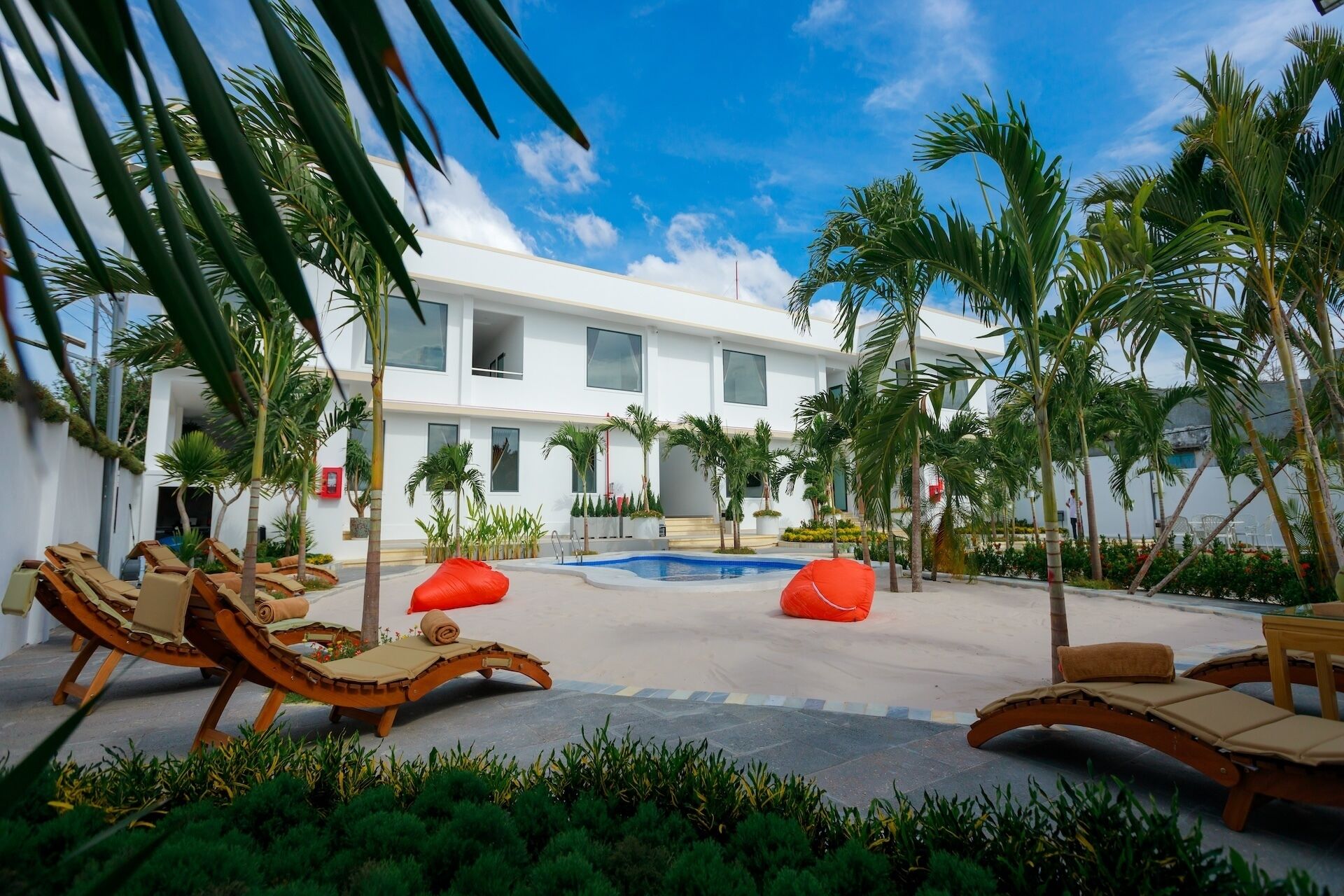 A pool area with lounge chairs, a small pool, and palm trees.