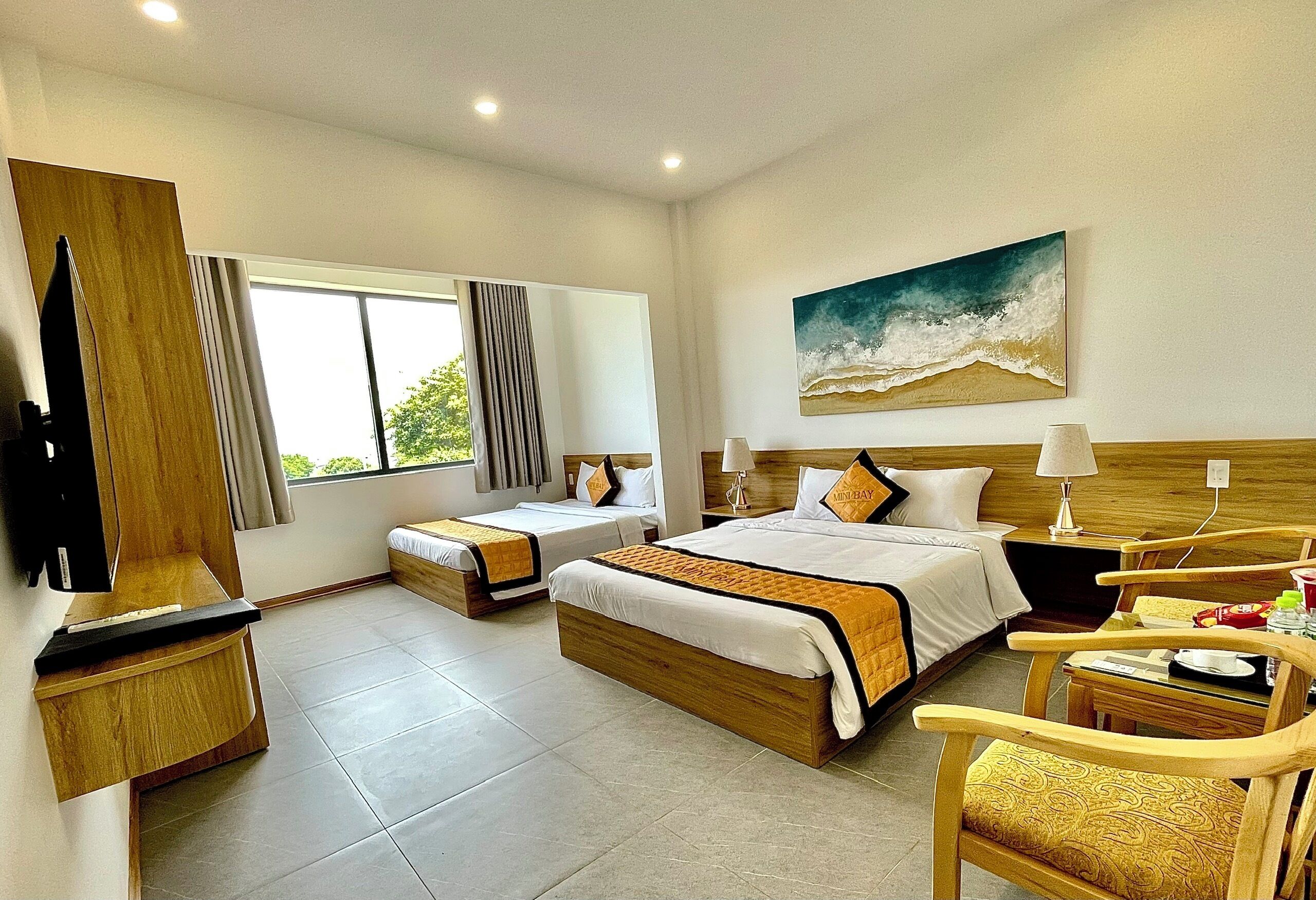 Habitación de hotel con dos camas, televisor, escritorio y una silla.