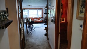 A hallway leading to a living area with a sofa, a dining table, and a kitchen area.