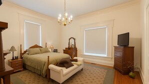 A bedroom with a bed, bedside tables, a dresser, a television, and a window.