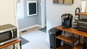 A compact kitchenette with a microwave, coffee maker, and toaster.