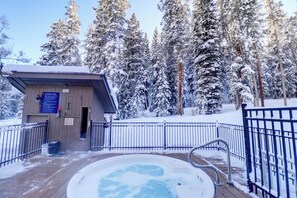 A wooden deck with a hot tub surrounded by snow-covered trees. - Ski in Ski Out with Hot tub Ten Mile Haus (Copper Mountain)