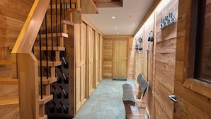 A wooden interior with a staircase, a bench, and a door with a handle.