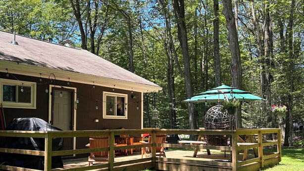 Une cabane dotée d’une terrasse, de sièges d’extérieur et d’un fauteuil suspendu.