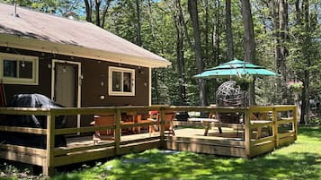 Une cabane dotée d’une terrasse, de sièges d’extérieur et d’un fauteuil suspendu.