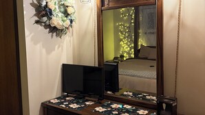 Une chambre à coucher avec un grand miroir, une commode en bois et une nappe à motifs floraux.