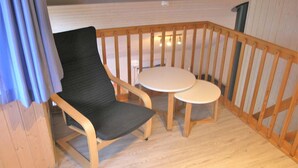 Une pièce d’angle avec une chaise en bois et deux petites tables rondes.