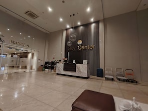 A hotel reception area with a reception desk, a clock, and a sign for 'Sky Center.' - Sky Center - Studio (Ho Chi Minh City)