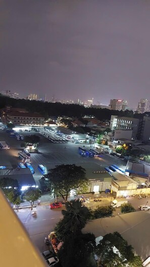 A nighttime view of a parking lot with several buses and cars, surrounded by buildings and trees. - Sky Center - Studio (Ho Chi Minh City)