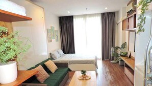 Un espacio habitable compacto con sofá, cama, mesita y una planta en maceta.