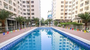 Una piscina con bordes de azulejos, rodeada de palmeras y edificios.