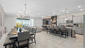 Une cuisine moderne dotée d’un îlot central, d’appareils électroménagers intégrés et de luminaires suspendus.