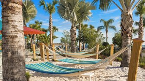 Une zone de plage avec des hamacs et des palmiers.