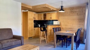 Una cocina moderna con armarios de madera, un comedor con mesa y sillas de madera, y un sofá en la sala de estar.