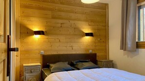Un dormitorio con cabecera de madera, dos mesitas de noche y una cama con almohadas.