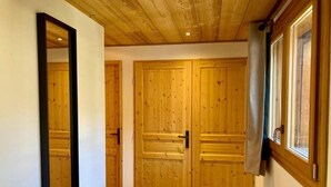 Un pasillo con puertas dobles de madera y un espejo grande a la izquierda.