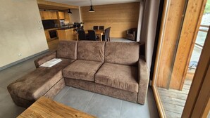 A modern living room with a sectional sofa, a wooden coffee table, and a kitchen in the background. - 100m from resort center, 5th floor, balcony, tv, 80m², Les 2 Alpes (Les Deux Alpes)