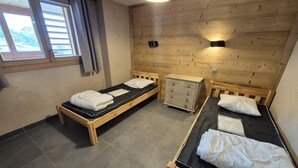 A room with two wooden beds, a dresser, and a window with curtains. - 100m from resort center, 5th floor, balcony, tv, 80m², Les 2 Alpes (Les Deux Alpes)