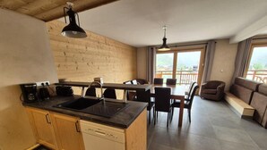 A modern kitchen with wooden cabinets, a dishwasher, and a dining area with a table and chairs. - 100m from resort center, 5th floor, balcony, tv, 80m², Les 2 Alpes (Les Deux Alpes)