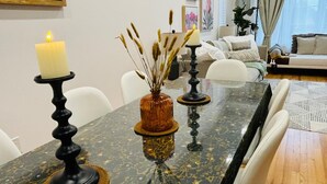 Taula de dinar amb espelmes i plantes decoratives, envoltada de cadires blanques.