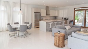 A modern kitchen with a central island, a dining area with a round table and chairs, and a living area with a sofa and a coffee table. - Aruba Opal Rental I (Noord)