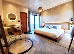 Relax in a serene space with a large bed, round mirror, and small table for a comfortable stay.
